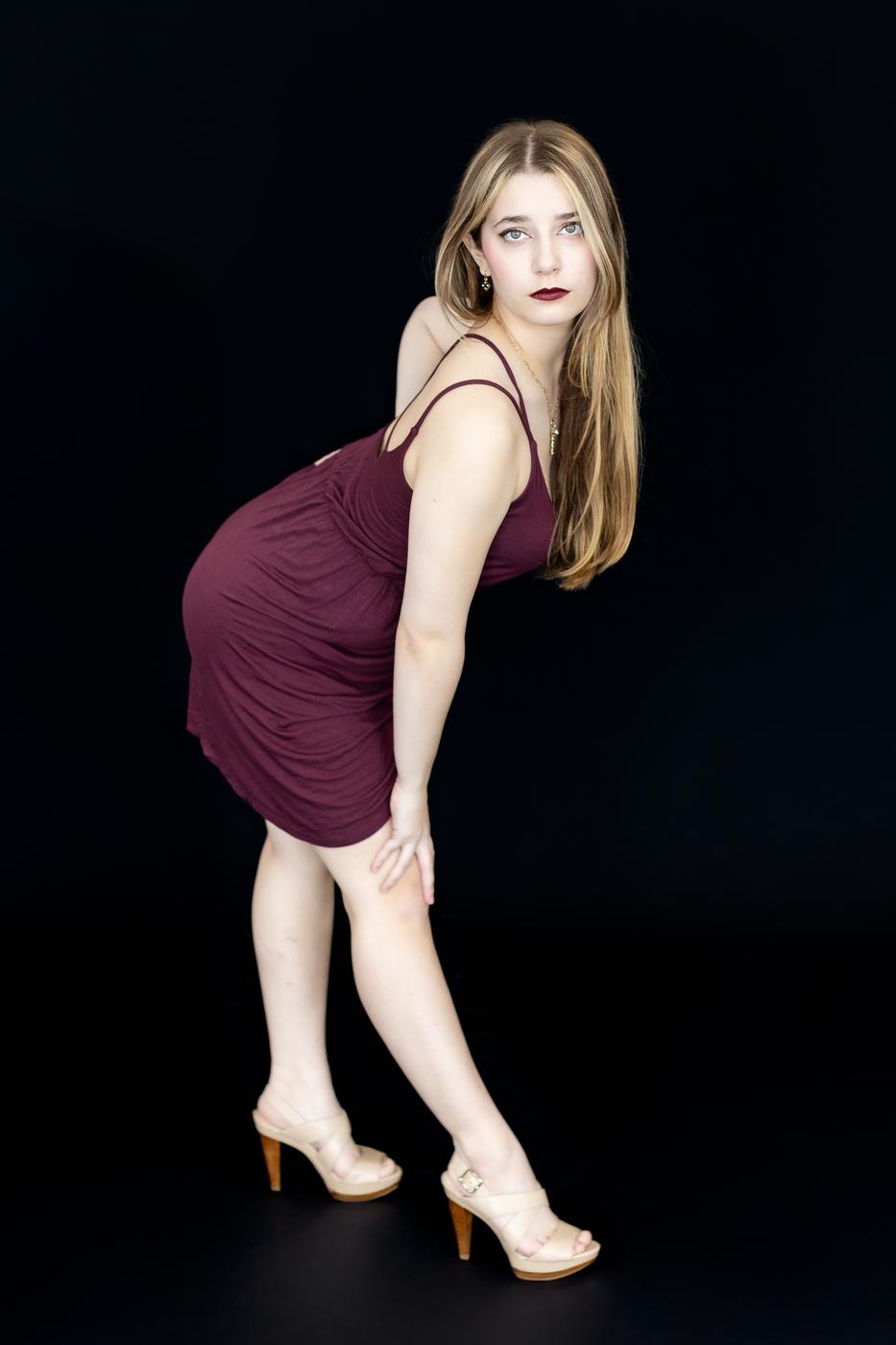 Ariella Sinclair editorial portrait in burgundy dress, strong gaze